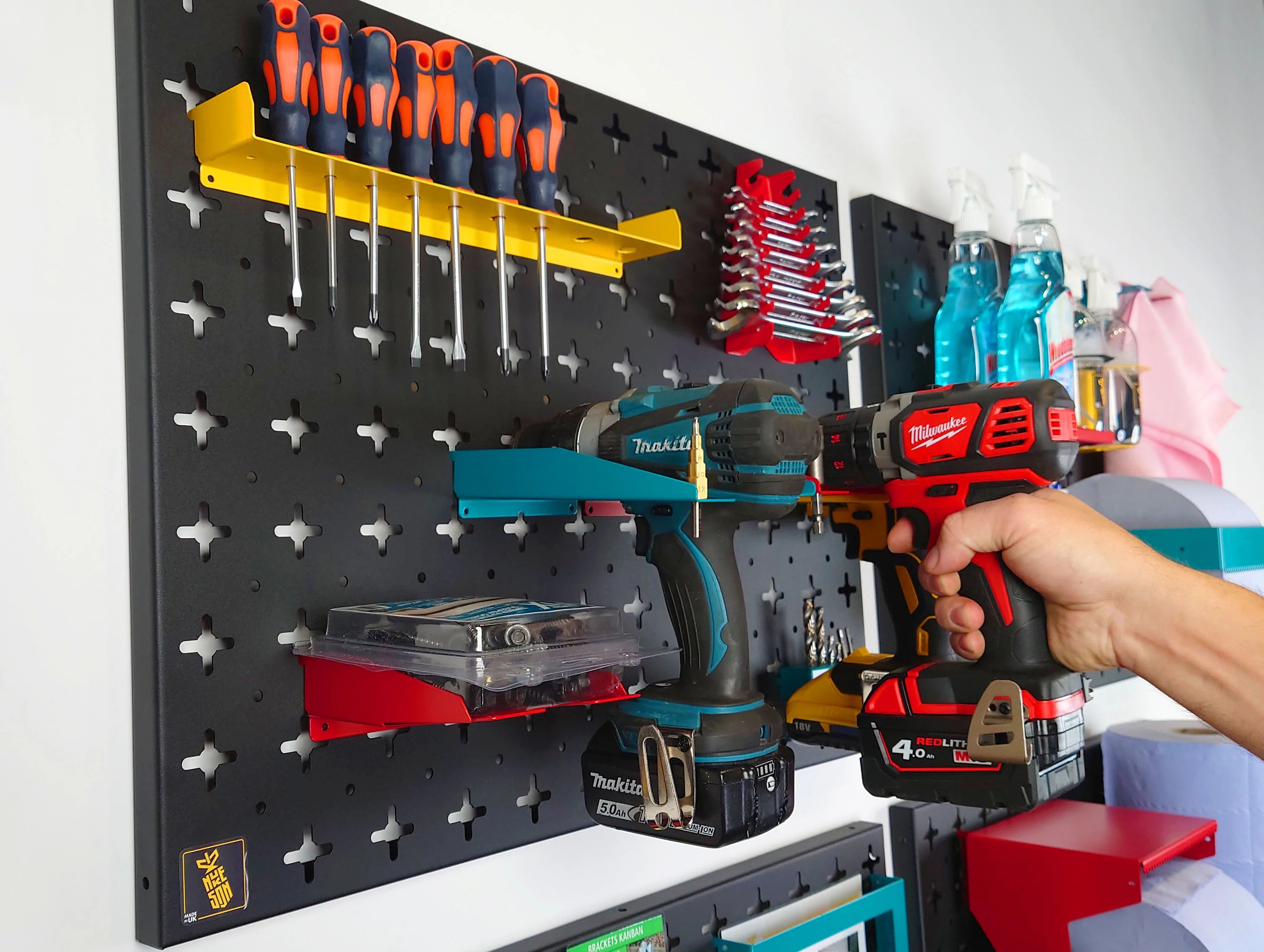 Hand Placing Milwaukee Drill on Wall, next to Makita and DeWalt Electric Drills