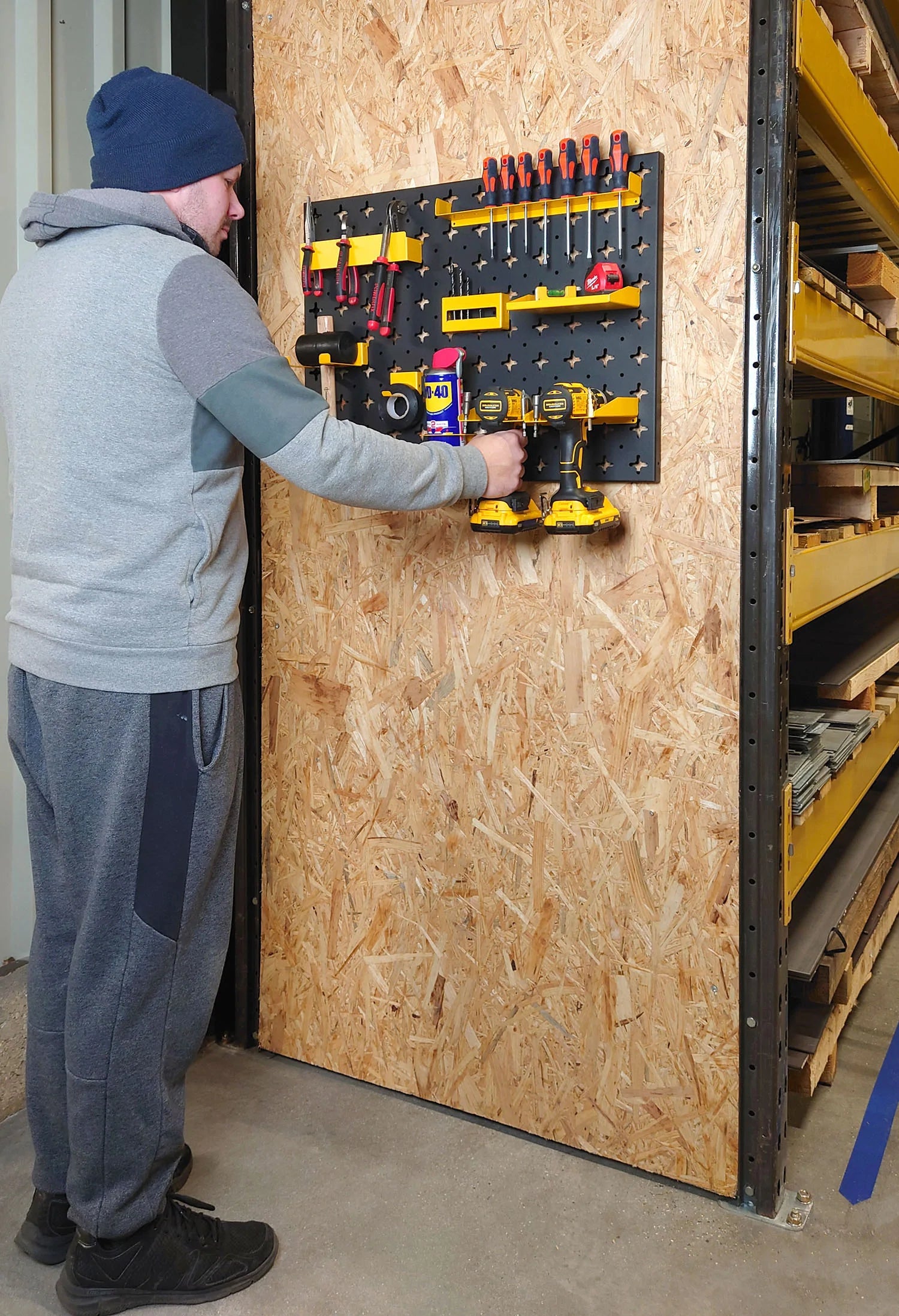 Man Placing Drill onto Tool Wall Panel in a Workshop Setting