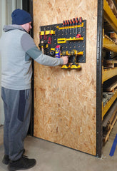 Man Placing Drill onto Tool Wall Panel in a Workshop Setting