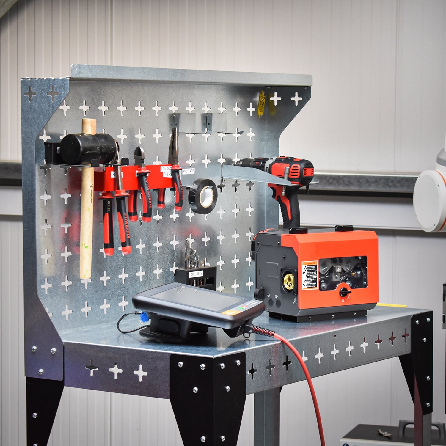 Nukeson Industrial Trolley & Workbench in a Workshop Setting next to a welding robot with equipment stored on the table and the back wall.