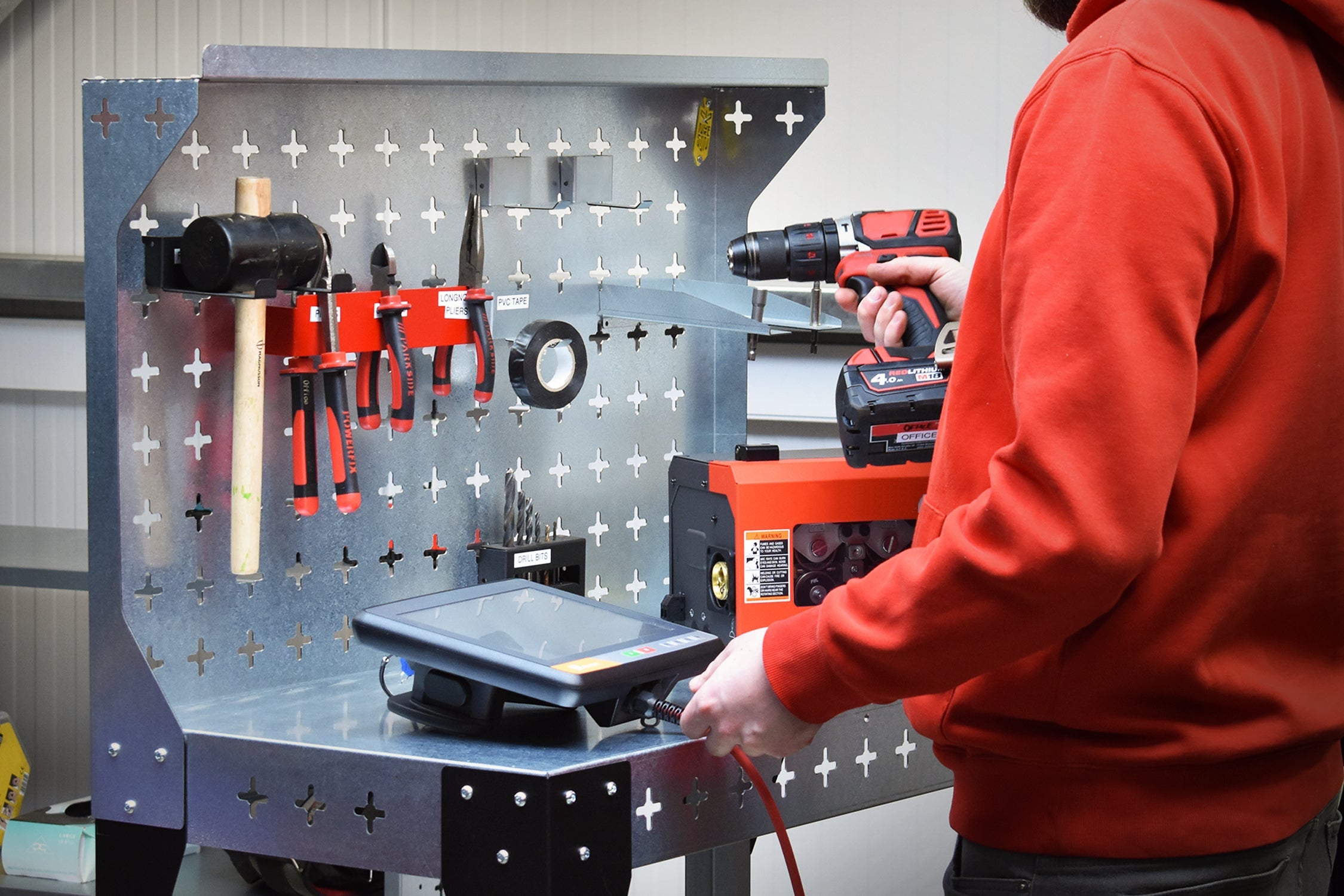 Nukeson Industrial Trolley & Workbench in a Workshop Setting next to a welding robot with equipment stored on the table and the back wall.